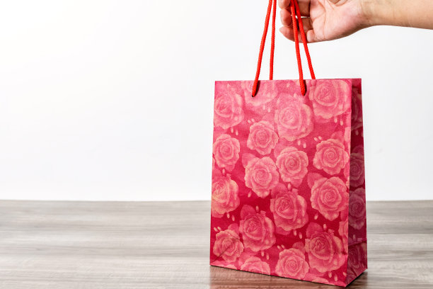 手拿红色购物纸袋放在木桌上图片下载