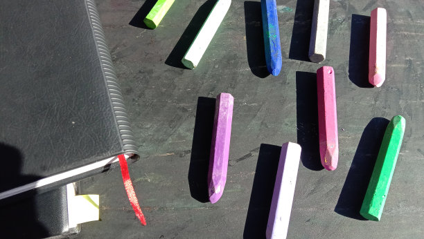 彩色蜡笔与书旁边的照片，黑色背景图片下载