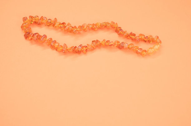 特写镜头的琥珀珠项链在橙色的表面图片下载