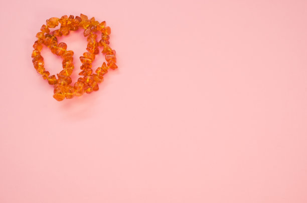 近距离拍摄的琥珀珠项链在粉红色的表面图片下载