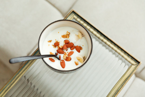 一碗加香蕉、杏仁的健康酸奶，桌上放一个勺子图片下载