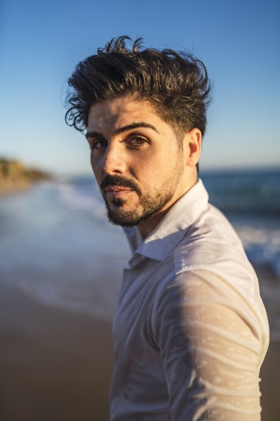 垂直图片的深色头发的男性在白色衬衫对着大海图片下载