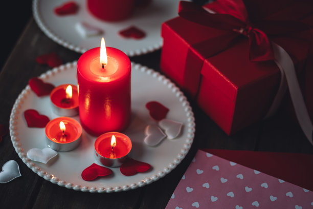 情人节庆祝活动。红色燃烧的蜡烛，爱心，礼品盒，明信片在黑暗的木制背景。节日快乐。餐桌装饰喜庆，气氛浪漫图片下载