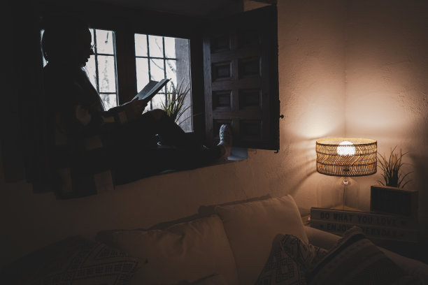 年轻的女性喝着一杯热茶，坐在窗台上看书图片下载