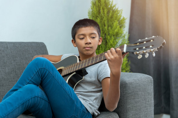 男孩坐在沙发上弹吉他图片下载