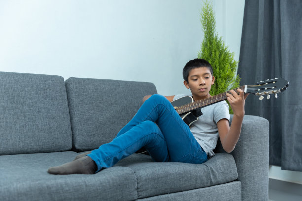 小男孩坐在沙发上弹吉他图片下载