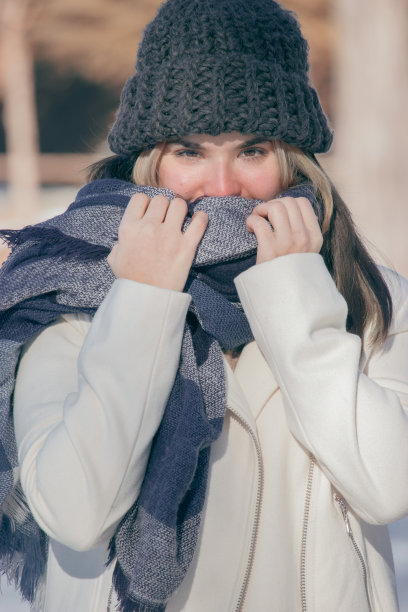 垂直选择性对焦拍摄一位穿着大衣、围巾、戴着冬帽的年轻女士在户外图片下载