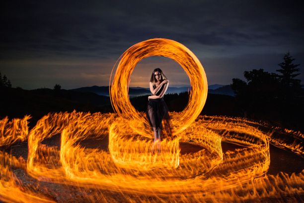美丽的照片，一个年轻的女人旋转长曝光灯在森林里在夜晚图片下载