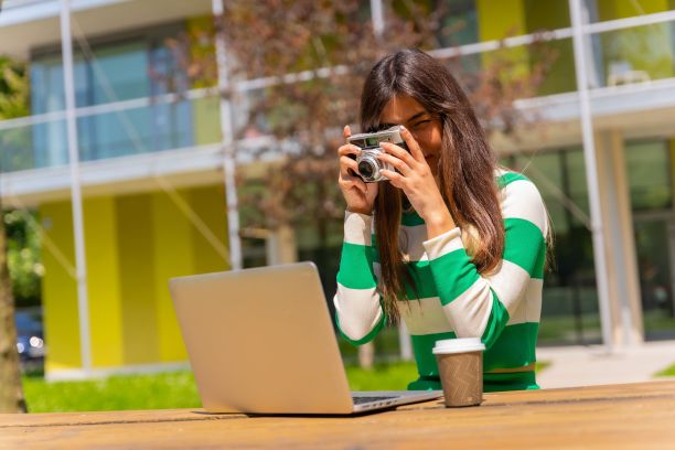 一名身穿绿白衬衫的白种人女性在大自然中用电脑拍照图片下载