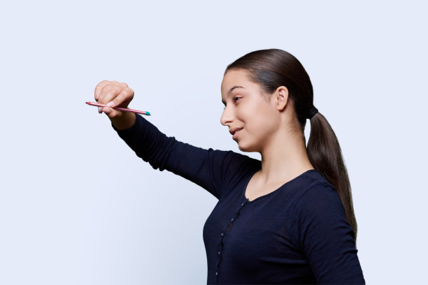 一个十几岁的女孩用铅笔在一个抽象的屏幕上画画图片下载