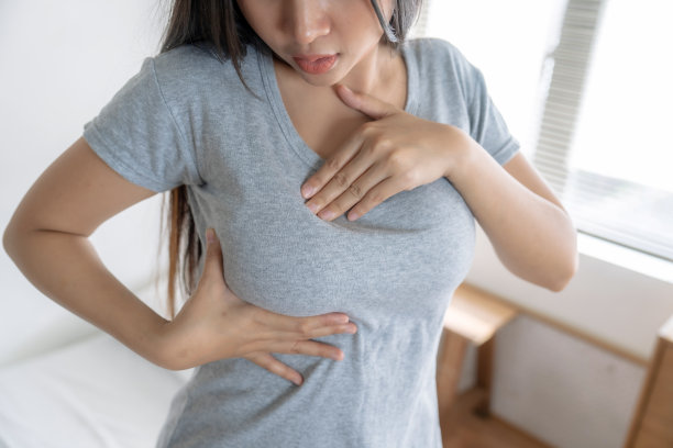 年轻的亚洲女性在家里做乳腺癌自检和检测。图片下载