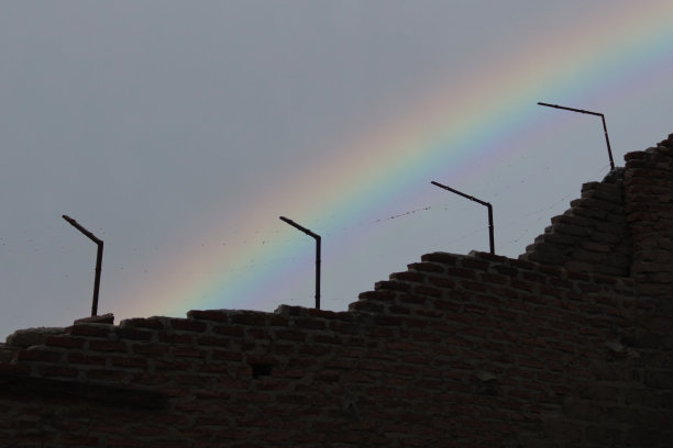 监狱的围墙和栅栏彩虹在天空中。自由与束缚的主题。图片下载