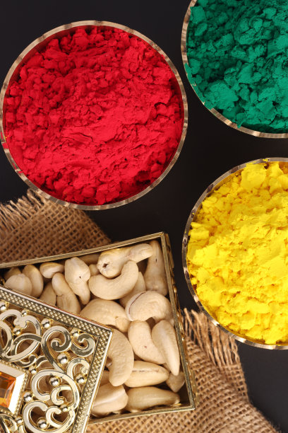 彩色有机干粉啤酒在传统的黄铜碗与腰果为庆祝印度胡里节的颜色图片下载