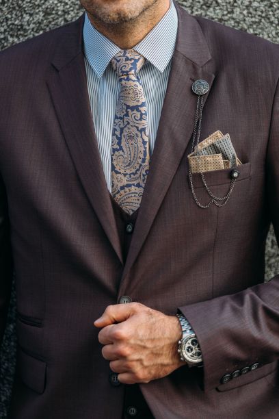 男人穿着棕色西装，白色条纹衬衫，佩斯利领带和翻领链珠宝图片下载