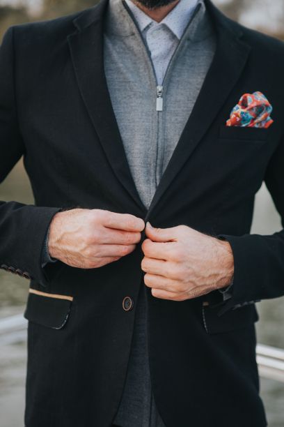 垂直镜头下，一个男人把他的黑色外套套在一件休闲的灰色拉链夹克上图片下载