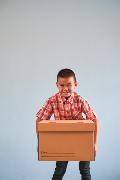 垂直特写的男孩携带一个沉重的纸箱或包装的货物交付图片下载