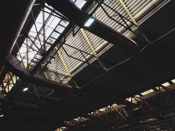 机库、生产车间或体育馆的屋顶。金属结构，梁，支撑元件。大型大厅和房间的通风系统。天窗。工业内部。图片下载
