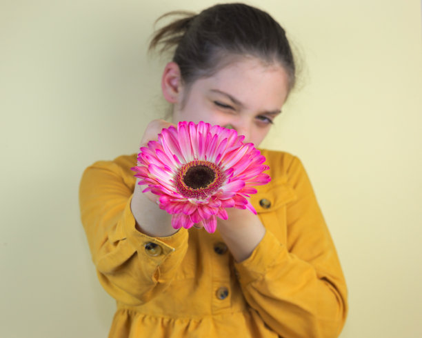 可爱的白人女孩保持粉红色的菊花对着相机图片下载