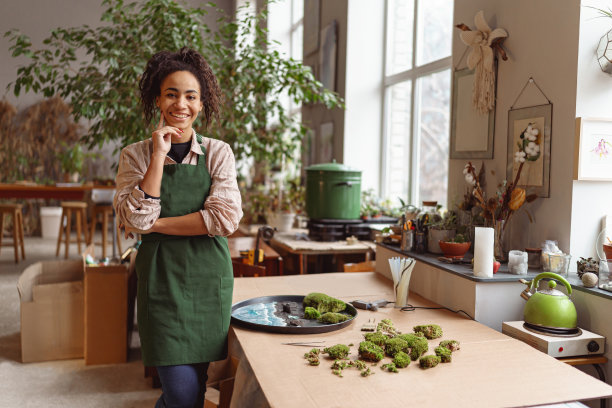 女装饰师在花店车间制作绿色花道的肖像，看着相机图片下载
