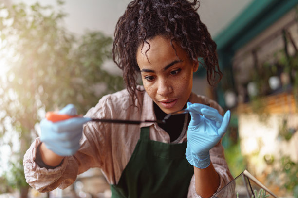 女子花店制作多肉植物成分在花卉设计工作室和看着相机图片下载
