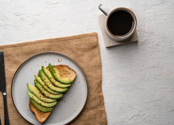 俯视图是白色盘子上美味的鳄梨吐司，旁边是一杯咖啡图片下载
