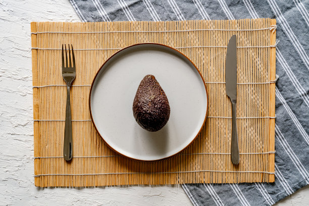 顶部视图新鲜的整个鳄梨在一个白色的盘子与刀叉图片下载