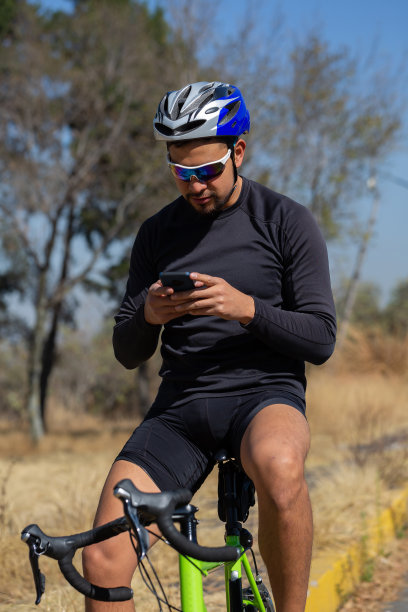 一个戴着墨镜的西班牙裔自行车手正盯着他的手机图片下载