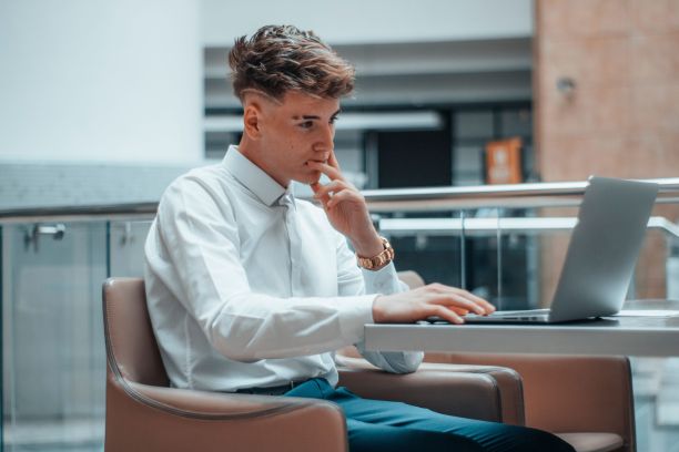 年轻英俊的商人在办公室用笔记本电脑工作图片下载