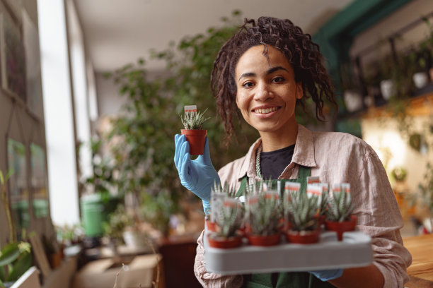 微笑的花匠在花艺工作室照顾花苗。园艺的概念图片下载