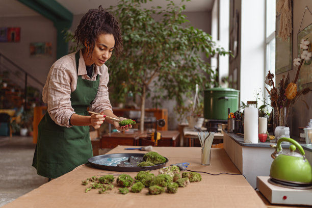 专业女性装饰师在花店车间用环氧树脂在托盘上制作绿色花道图片下载