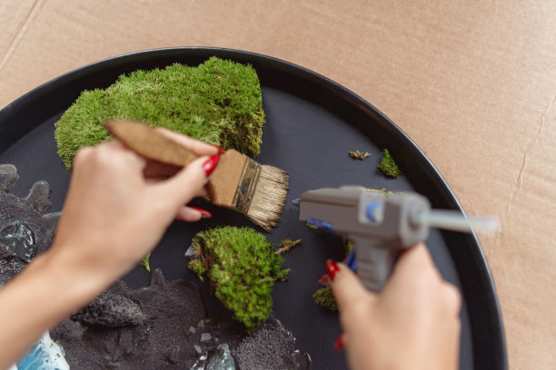 近距离女装饰师在花店车间的托盘上制作绿色花道图片下载