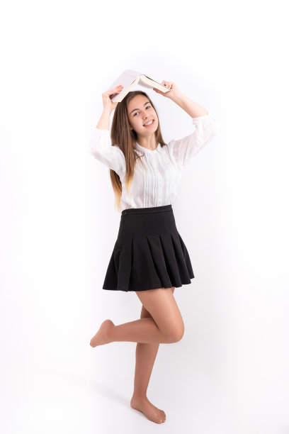 一个美丽的年轻女士拿着一本书，穿着黑色裙子和白色衬衫的垂直镜头图片下载