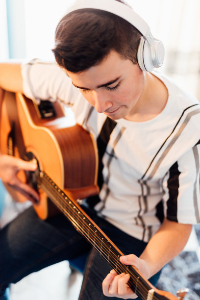 一个十几岁的男孩在你房间里在线上吉他课。技术的概念。图片下载