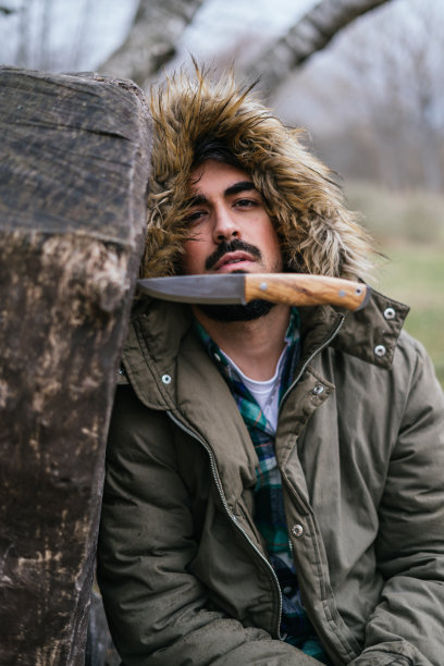 垂直选择性聚焦在原木上的一把刀，背景是一名男性图片下载