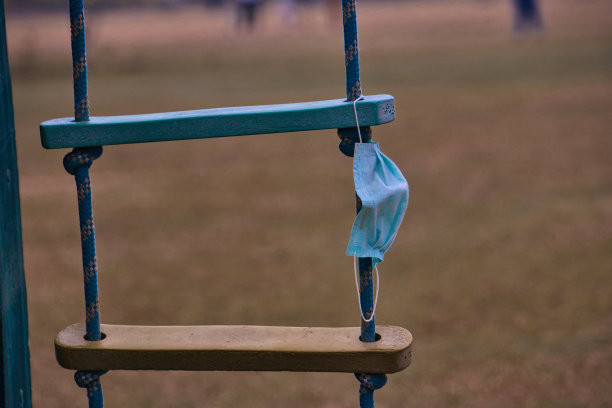 废弃在秋千上的旧蓝色COVID口罩图片下载