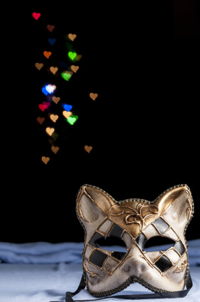 垂直拍摄的狂欢节面具与猫形式在一个黑暗与散景心脏背景图片下载