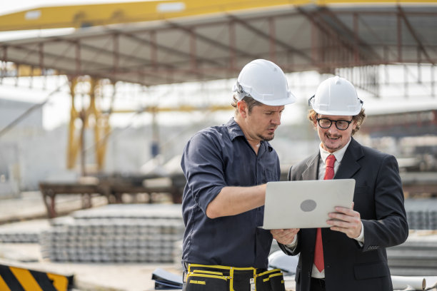 在生产预制墙体的工业工厂中，男工程师正在检查和控制员工的工作和制造的产品质量是否符合标准图片下载