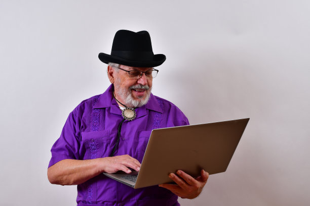 穿着得体的微笑老人正在用他的笔记本电脑图片下载