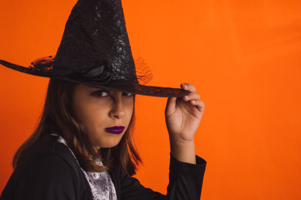 白人女孩子穿着橙色背景的女巫服装图片下载