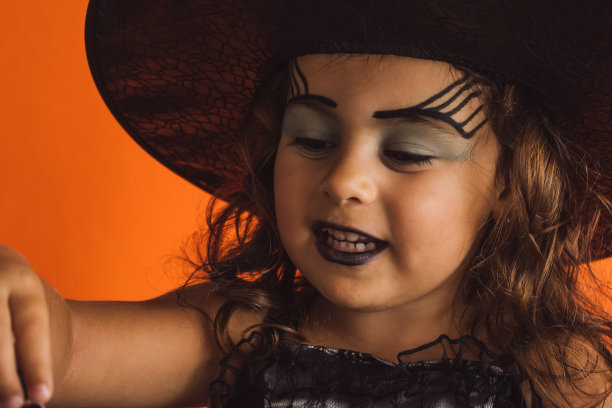 白人女孩子穿着橙色背景的女巫服装图片下载