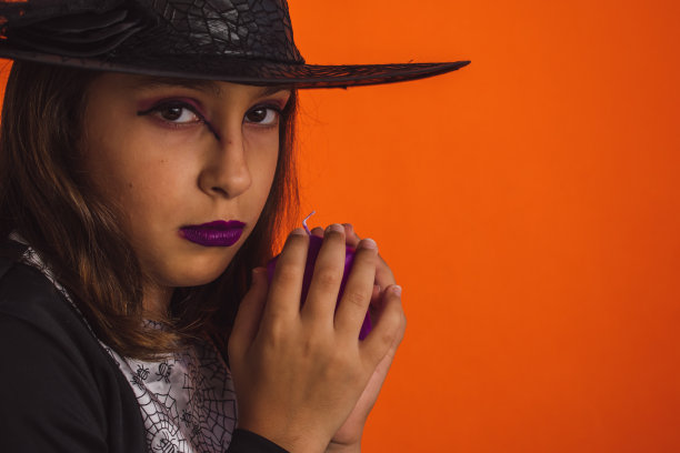 白人女孩子穿着橙色背景的女巫服装图片下载