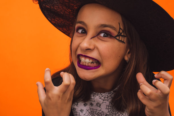 白人女孩子穿着橙色背景的女巫服装图片下载