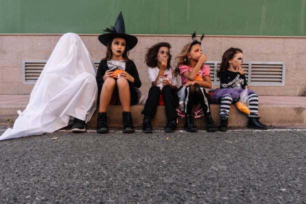 万圣节前夕，一群白人孩子坐在人行道上图片下载