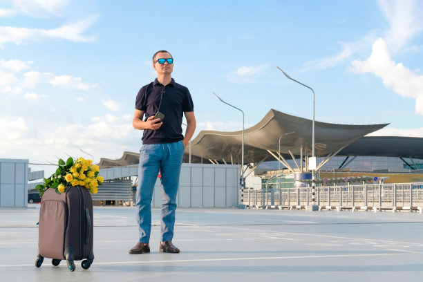 自信的年轻人拿着行李停在露天停车场。出差，出差图片下载