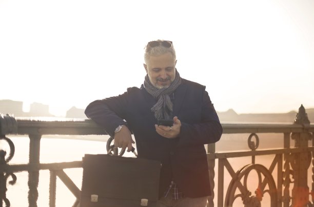 日落时分，一名匈牙利男子倚在桥的栏杆上用手机图片下载