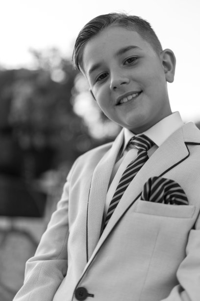 一个穿着正装的可爱男孩的垂直灰度照片图片下载