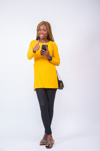 美丽的非洲女士用她的手机，脸上带着微笑图片下载