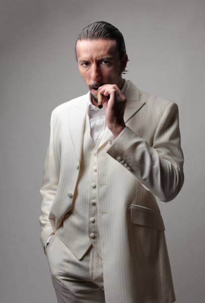 一个成年意大利黑手党老大的肖像，穿着白色西装，抽着雪茄图片下载