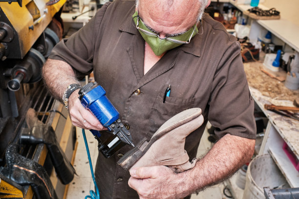 戴口罩的西班牙裔鞋匠在车间工作图片下载