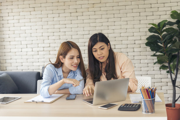两位亚洲女性自由职业者阅读财务图表策划分析市场数据。亚洲人团队工作的办公室公司。两名女商人在公司办公桌上使用笔记本电脑开会。图片下载
